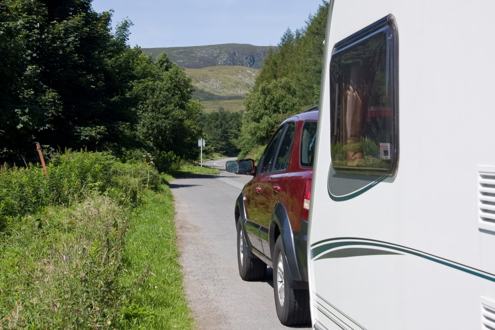 Red four wheel drive towing a caravan down a quiet road