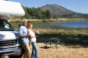 Retired couple relaxing by their caravan on the edge of a lake